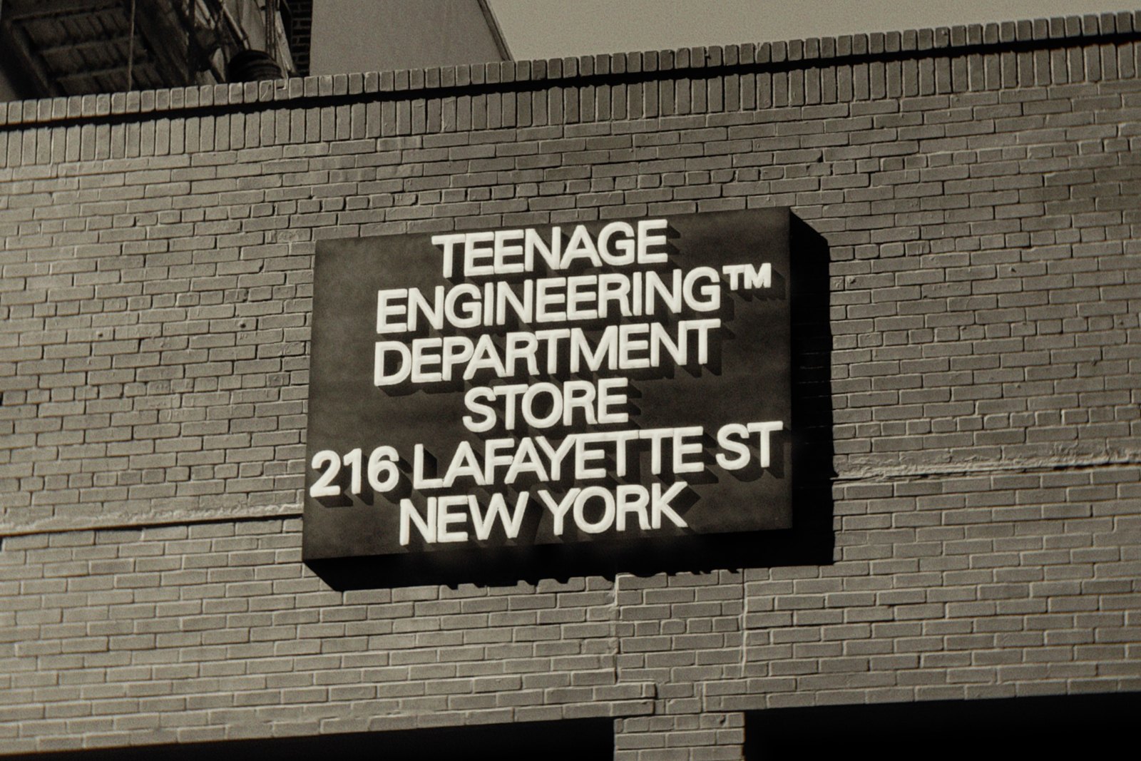 A black box sign on a brick facade, lettered in white: Teenage Engineering Department Store, 216 Lafayette St, New York.